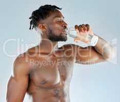 Its just what I need right now. Studio shot of a muscular young man drinking a glass of water.