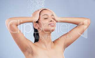 Rinse away the day. a young woman taking a shower against a blue background.