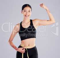 Toning up is the goal. an attractive young woman standing in the studio and using a measuring tape around her waist.