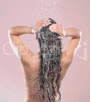 Spending time caring for myself. a young woman washing her hair against a studio background.