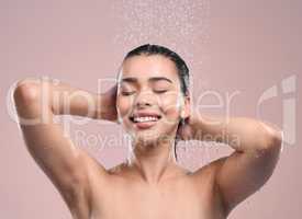 Treat yourself to a spa treatment. a young woman washing her hair in a shower against a studio background.