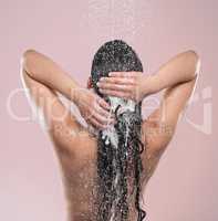 The right products yield incredible results. a young woman washing her hair against a studio background.