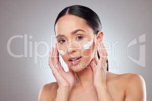 Make sure to moisturise on a regular basis. Studio portrait of a beautiful young woman applying moisturiser to her face against a grey background.