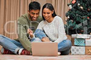 We can shop for everyone online. a young couple using a laptop and credit card during Christmas at home.