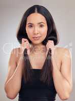 I think Im going to cut it. an attractive young woman posing alone in the studio and holding her hair.