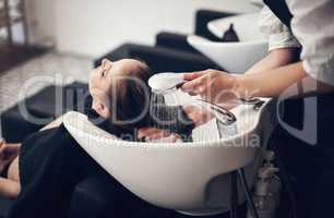 Theres nothing more relaxing than getting your hair washed at the salon. a beautiful young woman getting her hair washed at the salon.