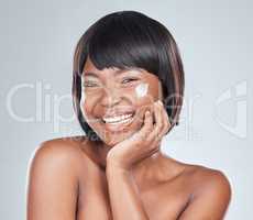 Ill share my beauty secret if you share yours. Studio shot of an attractive young woman applying moisturiser to her face against a grey background.