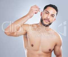 Say goodbye to wrinkles with retinol. Studio shot of a handsome young man applying serum to his face against a grey background.