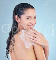 I might need help reaching my back. Studio shot of an attractive young woman taking a shower against a blue background.