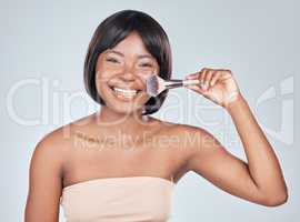 A little shine then its go time. Studio shot of an attractive young woman using a makeup brush against a grey background.