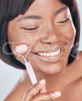 Its like a spa day for my face. Studio shot of an attractive young woman using a jade roller on her face against a grey background.