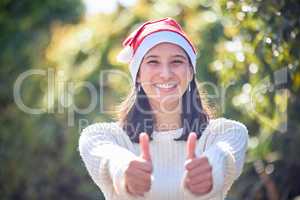 Mother Nature says merry Christmas. Portrait of a young woman celebrating Christmas in a garden and showing thumbs up.