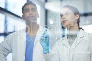 Making sense of it all. two scientists solving equations on a glass screen in a laboratory.