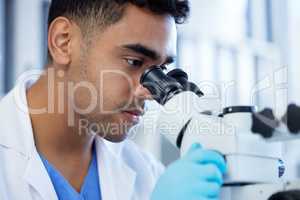 Theres a lot to observe in science. a young man using a microscope in a lab.