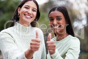 Well done on passing your finals. two young women showing thumbs up outside at college.