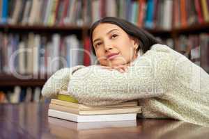 . Failure is an opportunity to try again. a young woman resting on a pile of books in a college library.