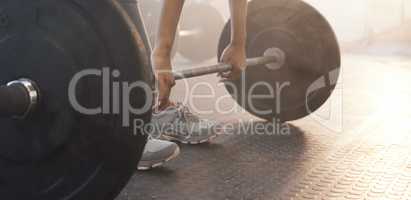 Deadlifts target full-body activation. Closeup shot of an unrecognisable woman exercising with a barbell in a gym.