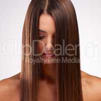 Hair that goes on forever. Studio shot of an attractive young woman posing against a grey background.
