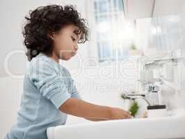 Teach kids to regularly wash their hands. an adorable little boy washing his hands at a tap in a bathroom at home.