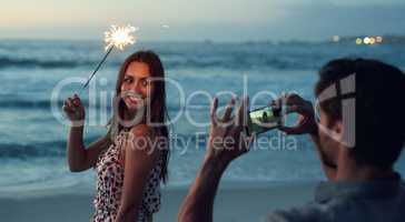 Beautiful woman holding sparkler posing for photo on romantic beach celebrating new years eve at sunset