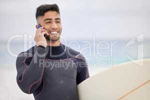 Im catching waves right now. a young man using a cellphone while surfing at the beach.
