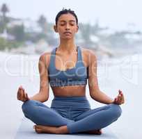 Inner peace is the key. Full length shot of an attractive young woman meditating while practicing yoga on the beach.