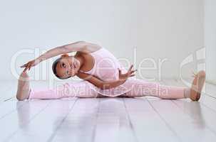 Warming up before practicing her routine. a little girl doing the splits in a ballet studio.