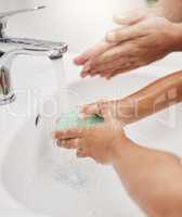 Learning all about good hand washing habits. Closeup shot of a father helping his son wash his hands at a tap in a bathroom at home.