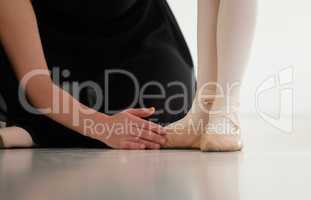 Correctly her stance and position. Closeup shot of a ballet teacher assisting a student with her position in a dance studio.