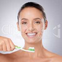 Put dental hygiene first. a beautiful young woman brushing her teeth against a grey background.