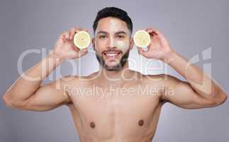 Use citrus in your routine sparingly. a young man holding cut up lemons against a studio background.