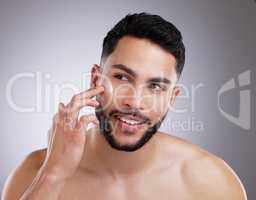 No more dry cracked skin for me. a handsome young man applying moisturiser on his face against a studio background.