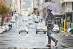 Weather like this makes me want to stay in bed. a handsome businessman walking to work on a rainy day.