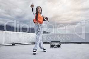 The queen of street. Full length shot of an attractive young woman dancing on a rooftop against a stormy backdrop.