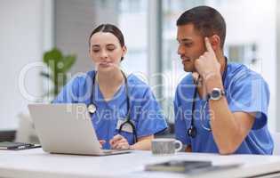 Coming together to work on the case. two medical practitioners working together on a laptop in a hospital boardroom.