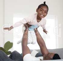 Teach your kids how to fly. Cropped portrait of an adorable little girl playing with her dad on the sofa at home.