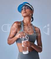 Good things take a good amount of commitment. Studio shot of a fit young woman drinking bottled water against a grey background.