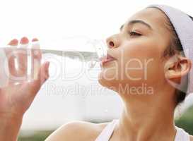 Im a little thirsty. a beautiful young woman drinking a bottle of water while out playing tennis.