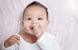 Just wanna stare at his cuteness all day. High angle shot of an adorable baby sucking his fingers at home.