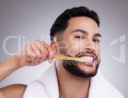 Keeping away those oral nasties. a handsome young man brushing his teeth against a studio background.