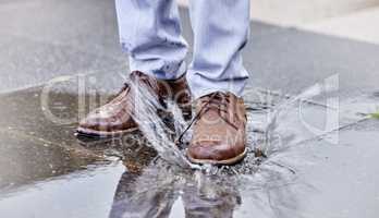 Watch your step. a unrecognizable man walking in a puddle of water outside.