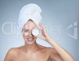 Its the ultimate skincare product. Studio portrait of an attractive young woman posing with a container of moisturizer against a grey background.