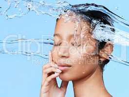 Even the birds thinks shes a flower. a beautiful young woman being splashed with water against a blue background.