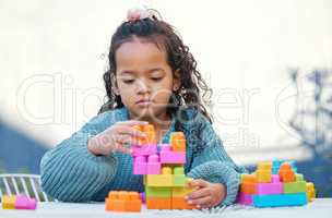 What will we build today. a little girl playing with building blocks in her yard.