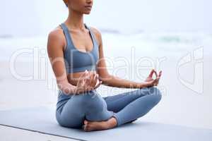 Feeling zen. an unrecognizable young woman meditating while practicing yoga on the beach.