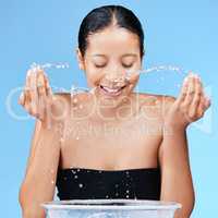 There is no wrong way to love your body. a beautiful young woman splashing water on her face against a blue background.