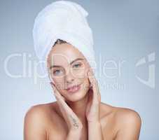 Soft to the touch. Studio portrait of an attractive young woman posing with a towel on her head against a grey background.