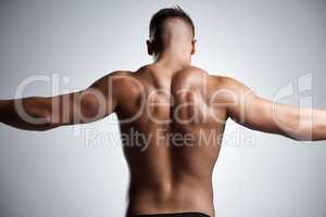Let the gains begin. Studio shot of a muscular young man posing against a grey background.