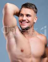 Genetically blessed, groomed by choice. Studio shot of a muscular young man posing against a grey background.