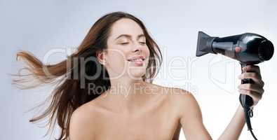 Let me walk you through my haircare routine. a woman blowdrying her hair while standing against a white background.